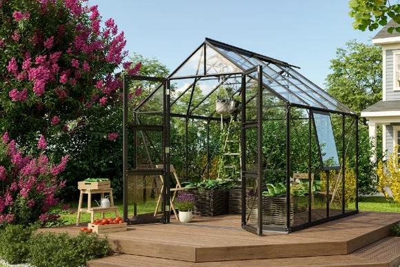 Gewächshaus aus Glas mit geöffneten Türen auf einer Holzterrasse